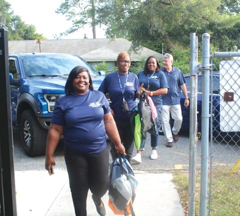 Lake City Correctional Facility employees Sonical Mitchell (from left), Twylah Queen, Deanna Lumpkin and James Deal, walk through the Eastside Elementary School gates Thursday morning while carry book bags for area students. The foursome donated book bags to several local elementary schools Thursday. (TONY BRITT/Lake City Reporter)