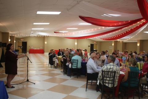 Jamie Lane (standing), a United Way of Suwannee Valley case worker, addresses the audience during the organization’s campaign kickoff Thursday night at the Florida Gateway Fairgrounds exhibition hall. (TONY BRITT/Lake City Reporter)