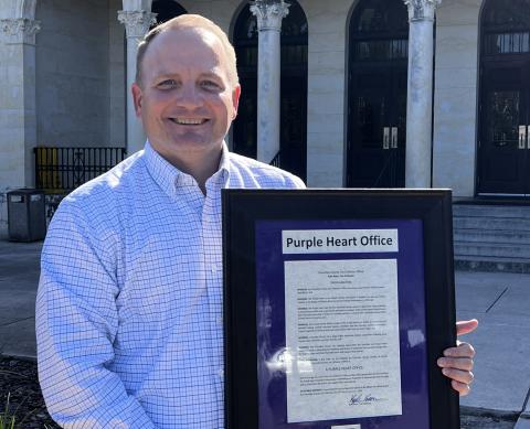 Columbia County Tax Collector Kyle Keen displays a proclamation explaining that his office has been designated as a Purple Heart Office. (COURTESY)