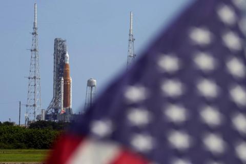 An American flag flies in the breeze as NASA's new moon rocket sits on Launch Pad 39-B after being scrubbed at the Kennedy Space Center on Saturday in Cape Canaveral. (CHRIS O’MEARA/Associated Press)