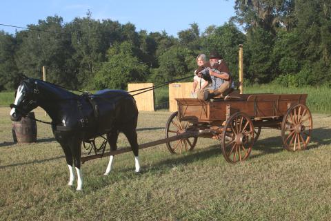 Todd and Tammy Denmark ride an antique wagon into Raven’s Hollow, the old west town depicted in their Denmark Acres site that will open Friday. (JAMIE WACHTER/Lake City Reporter)
