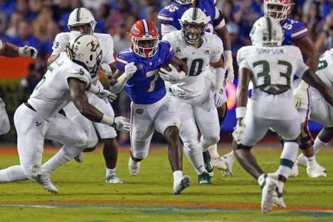 Florida running back Trevor Etienne finds an opening for yardage against the South Florida defense, including linebacker Antonio Grier (left), defensive lineman Nick Bags (second from right) and cornerback T-Mac Simpson (33), during Saturday's game in Gainesville. (JOHN RAOUX/Associated Press)