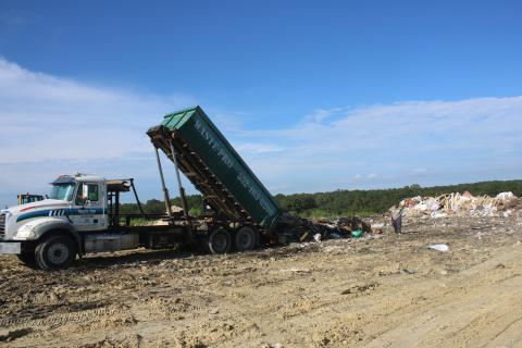 A pair of Waste Pro employees oversee the dumping of a truckload of garbage at the Columbia County Landfill. (TONY BRITT/Lake City Reporter)