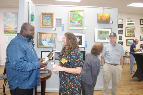 Osmund Johnson (left) shares a laugh with Sarah Stephens, the VA’s creative arts therapist, during Monday night’s veterans art exhibit award ceremony at the Gateway Art Gallery. (TONY BRITT/Lake City Reporter)