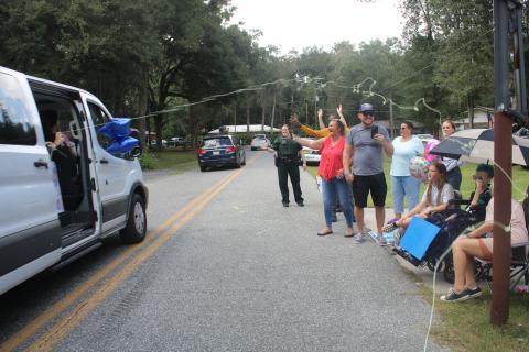 Belmont Academy students shoot silly string out of a van at Peyton Hamilton (under umbrella) and her family members during Monday’s parade. (TONY BRITT/Lake City Reporter)