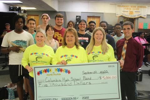 Puzzle Pieces of North Florida representatives Tabatha Feagle (from left), Kathryn Harper and Terri Prescott stand with Jay Miller, Columbia High School band director, after presenting the band with a $5,000 check on Thursday afternoon. (TONY BRITT/Lake City Reporter)