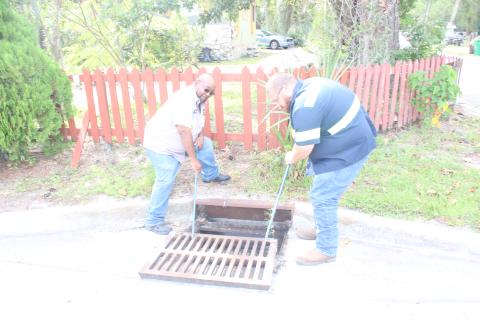 Pic Redmond (left) and Josh Green, employees with the City of Lake City Public Works Department, close a storm drain on Northwest Texas Avenue after inspecting it for blockages before inclement weather from Hurricane Ian arrives. (TONY BRITT/Lake City Reporter)