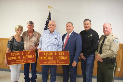 Teresa Register (from left) stands with her brothers Tevis Gay, Dewy Gay, State Rep. Chuck Brannan, Columbia County Sheriff Mark Hunter and Col. James Wiggins, Florida Director of the Office of Agricultural Law Enforcement, following a ceremony where a portion of U.S. Highway 441 was dedicated in honor of slain agricultural officer Austin D. Gay.  The ceremony took place Friday morning at the Deep Creek Community Center. (TONY BRITT/Lake City Reporter)
