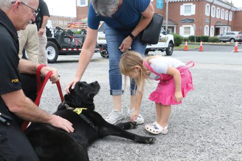 Maddie Boone (right) goes in for a pet on Fresca, an accelerant detection K9 that helps investigate cases of arson, during last year’s National Night Out event. (FILE)
