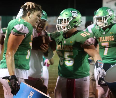Suwannee head coach Kyler Hall laughs with offensive lineman Taylon Jones (left) and offensive lineman Andrew Harrell (right) after the team gave Hall a cooler bath following the Bulldogs’ 36-7 win over Madison County on Friday. (PAUL BUCHANAN/Special to the Reporter)