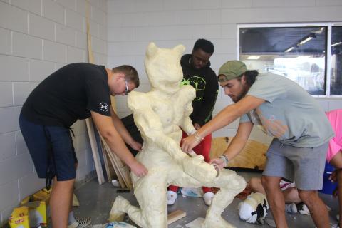 Dominic Cuadras (foreground) adds tape to a float prop as he, Ethan Pittman (left) and Xavier Combs work on the senior class homecoming float. (TONY BRITT/Lake City Reporter)
