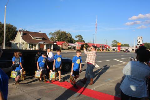 Brandon Ruwe (foreground) is greeted by Sarah Ripple, an Eastside Elementary School third-grade teacher, as he and Andrew Howard, Ryan McDaniel, Kendalynn Coates and Chloe Felton exit a limousine before Tuesday evening’s school board meeting. (TONY BRITT/Lake City Reporter)