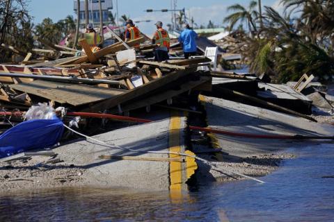 Responders from the de Moya Group survey damage to the bridge leading to Pine Island to start building temporary access to the island in the aftermath of Hurricane Ian on Sunday in Matlacha. The only bridge to the island is heavily damaged so it can only be reached by boat or air. (GERALD HERBERT/Associated Press)