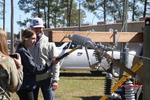 Mackenzie Thomas, a Columbia High School sophomore, learns the proper technique for handling electrical equipment at the Clay Electric Cooperative booth Wednesday morning. (MORGAN MCMULLEN/Lake City Reporter)
