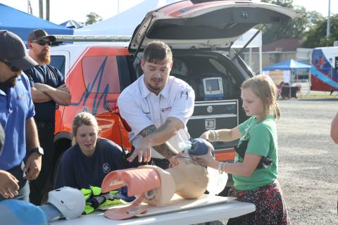 Jadyn Simpson (right) learns how to work a pump resuscitation bag at a Century Ambulance booth Tuesday night during the Lake City Police Department’s National Night Out event. (MORGAN MCMULLEN/Lake City Reporter)