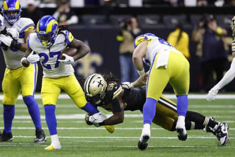 Los Angeles Rams running back Darrell Henderson Jr. carries the ball as New Orleans Saints linebacker Demario Davis holds on during Sunday’s game in New Orleans. (BUTCH DILL/Associated Press)