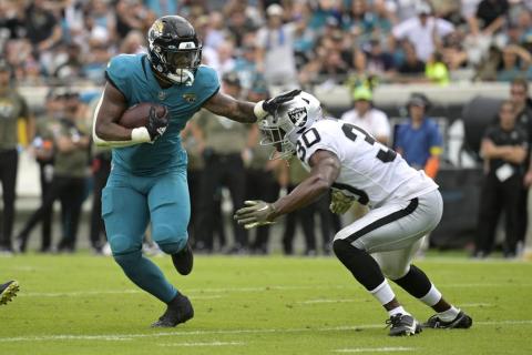Jacksonville Jaguars running back Travis Etienne Jr. tries to get past Las Vegas Raiders safety Duron Harmon during Sunday's game in Jacksonville. (PHELAN M. EBENHACK/Associated Press)