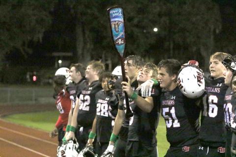 Fort White quarterback Clayton Philpot holds the ‘Paddle’ aloft as the Indians celebrate their win against Santa Fe on Friday night. (MORGAN MCMULLEN/Lake City Reporter)