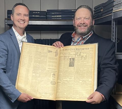 Jay Swisher, Columbia County Clerk of Courts and 2022-23 Rotary Club of Lake City President, and Todd Wilson, Publisher of the Lake City Reporter and Rotarian, hold up the Nov. 17, 1922, edition of the Reporter, which includes the story on the formation of the Rotary Club 100 years ago today. (JAMIE WACHTER/Lake City Reporter)