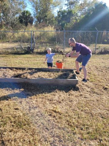 A volunteer plays with a child as they work toward building out a raised plant bed at Richardson Community Center Saturday. (COURTESY)