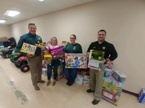 Columbia County Sheriff Mark Hunter (from left) stands with other sheriff’s office employees Paige Milligan, Sarah Wheeler, and Sgt. Chris Parker as they show toys that were purchased and donated from the agency’s inaugural ‘Deputy Clause for a Cause’ program. (TONY BRITT/Lake City Reporter)
