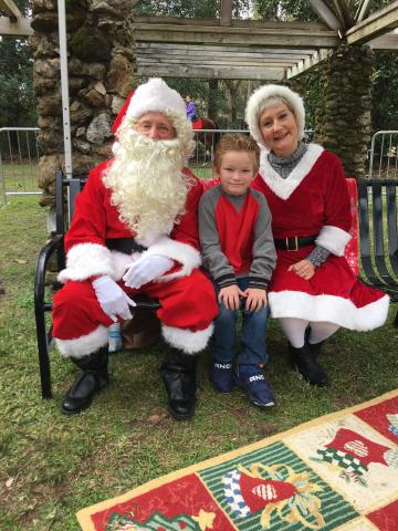 Santa and Mrs. Claus get their picture taken with a child at a previous year’s Christmas at Heritage Park and Gardens event. (COURTESY)