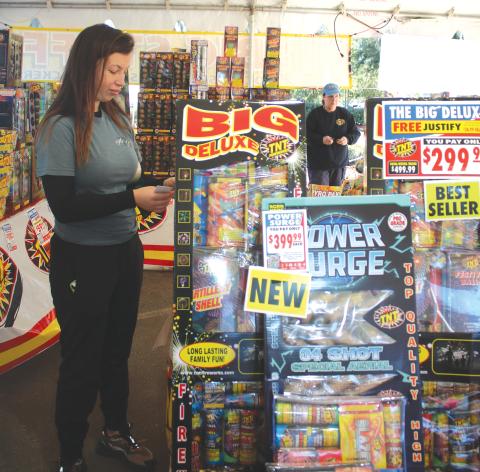 Kenzie Dungan, a Columbia High School FFA member, places pricing stickers on firework displays in the Columbia High School FFA fireworks tent on Tuesday afternoon. (TONY BRITT/Lake City Reporter)