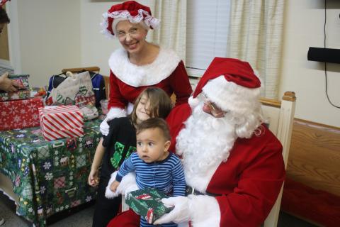 Ilyas Rosado, 10 months, sits on Santa’s lap as Ryatt Rosado, 7, poses for a picture with Ms. Claus on Friday evening during the Cookies With Santa event. (TONY BRITT/Lake City Reporter)