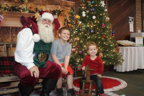 Santa Claus (from left) gets smiles from Bentley Strickland, 9, and Carleigh Holeman, 3, during an after-hours event at the Columbia County Public Library that was attended by more the 25 children. (TONY BRITT/Lake City Reporter)