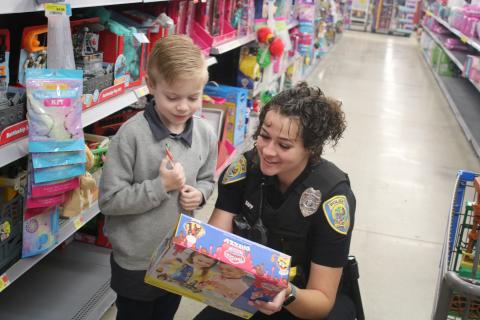 Dexter Gamble, 7, and Lake City police officer Taylor Sapp, look at the specs on a toy Gamble was considering purchasing during the Shop With A Cop event on Wednesday morning at Walmart. The Lake City Police Department has hosted the event for 10 years. (TONY BRITT/Lake City Reporter)