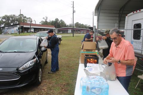 Cy Perkins (far left) gives a meal to a visitor at the Parkview Baptist Church parking lot on Thursday morning as Paul Tomassini and Ricky Beauchamp prepare other meals during the Mt. Caramel Baptist Church’s ‘Feed My Lambs’ community outreach program. (TONY BRITT/Lake City Reporter)