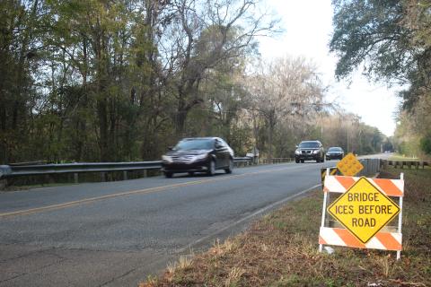Vehicles travel southbound on Southeast Country Club Road on Thursday afternoon, after county crews erected hazardous conditions signs for both lanes of travel for a local bridge. The signs have been erected at 34 locations across the county. (TONY BRITT/Lake City Reporter)