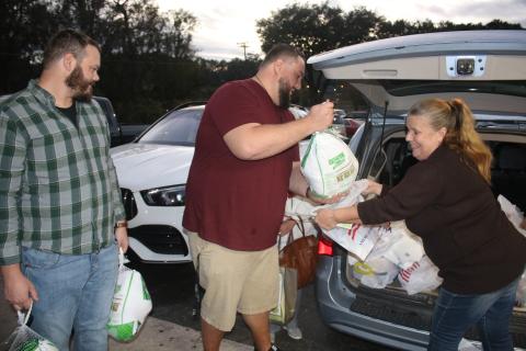 Josh Fuller (from left) and James Crenshaw pass turkeys to Dawn Johnson for the Elks Lodge Christmas baskets Thursday night. (TONY BRITT/Lake City Reporter)