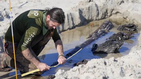 Archaeologist Christopher McCarron takes measurements of a structure exposed in the sand Tuesday in Daytona Beach Shores. (JOHN RAOUX/Associated Press)
