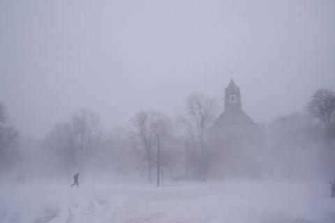 A lone pedestrian in snow shoes makes his way across Colonial Circle as St. John’s Grace Episcopal Church rises above the blowing snow amid blizzard conditions in Buffalo, N.Y., on Saturday. (DEREK GEE/The Buffalo News via AP)