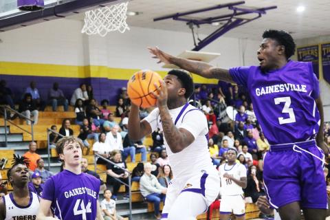 Columbia guard Tray Tolliver rises for a shot as Gainesville’s Theo Stephens attempts to block it on Thursday night. (JORDAN KROEGER/Lake City Reporter)