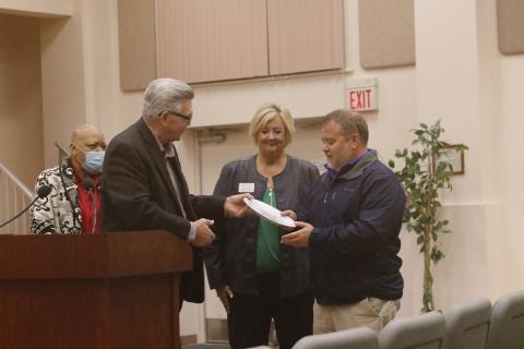 David Boozer (left), the Florida Gateway Food Bank Manager, presents a ceremonial plate to Eastside Elementary Principal Roger Little as Catholic Charities Regional Director Suzanne Edwards looks on. (JAMIE WACHTER/Lake City Reporter)