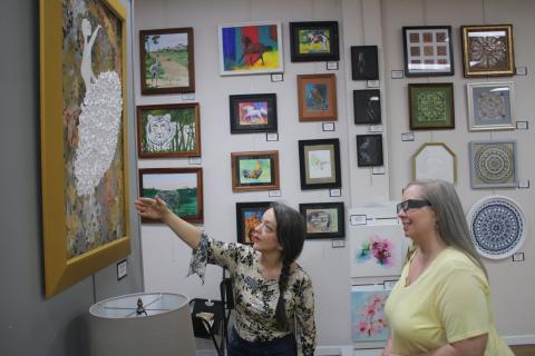 Gateway Art Gallery Curator Sheila Carr (left) points out a work of 3D art to Melanie Thum. (TONY BRITT/Lake City Reporter)