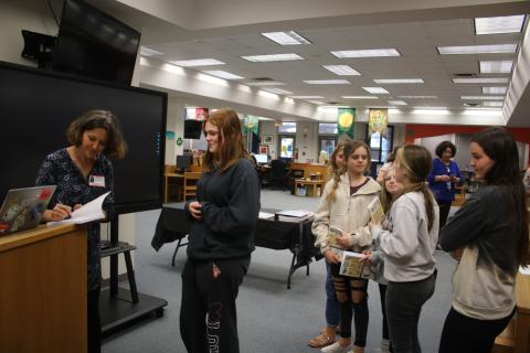 Sandra Poucher (from left) autographs a copy of her book, ‘Wildlife of Florida’s Springs,’ for Sanafa Sanders on Monday morning in the Fort White High School Media Center. (TONY BRITT/Lake City Reporter)