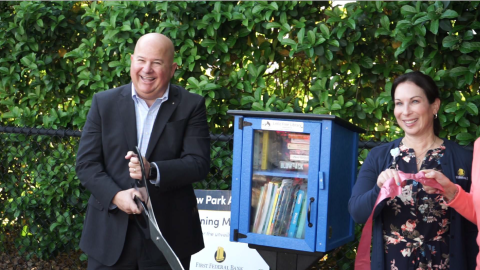 John Medina, president and CEO of First Federal Bank, cuts the ribbon on a Little Free Library at the Kiwanis Children’s Park adjacent to the bank’s headquarters on W. U.S. Highway 90 during a ceremony Thursday morning. Also pictured is Stephanie Esposito, the bank’s corporate marketing manager. (COURTESY)