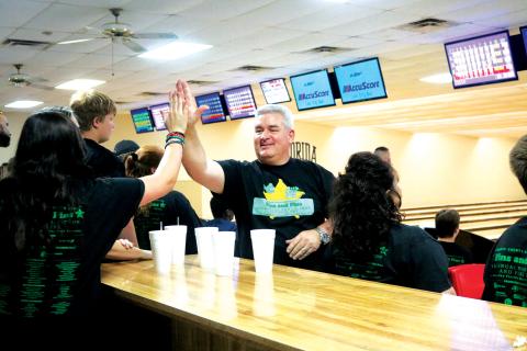 Jesse Stalnaker (right) gives out a high-five during the eighth annual Fins and Pins Bowl-a-Thon in 2019. (FILE)