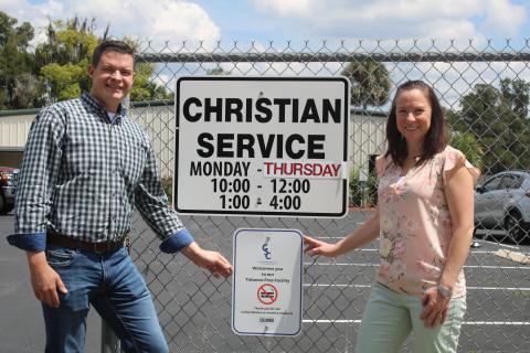 Chris Walters (left) and Brooke Frye show off the Christian Service Center’s new tobacco-free sign hanging in front of the center. (TONY BRITT/Lake City Reporter)