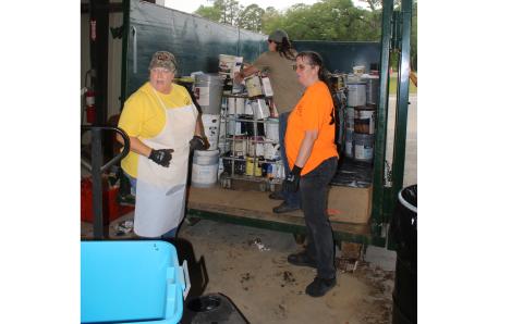 Pam Davis, Winfield Solid Waste director (clockwise from left), and solid waste facility employees Heather Crowder and Robyn Fussnecker place cans of paint into a dumpster during Saturday’s Toxic Roundup. (TONY BRITT/Lake City Reporter)