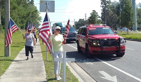 Volunteers, with assistance from the Lake City Fire Department, erect the crosses and flags alongside State Road 47 Saturday morning for the America’s Heroes Program. (COURTESY)