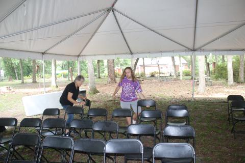 Volunteers Joan Alderman (left) and David Enfinger set up chairs beneath a tent at one of the stages for the Florida Folk Festival on Wednesday. (TONY BRITT/Lake City Reporter)