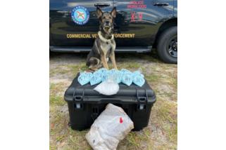 A Florida Highway Patrol K-9 officer in front of drugs confiscated during a multi-jurisdictional strike force operation in Columbia County last week. (COURTESY)