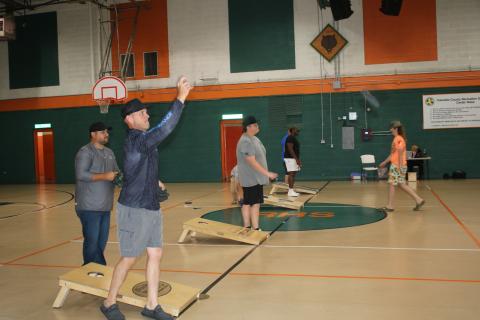 Stephen Jones (far left) follows through after tossing a bag in a cornhole match at the Richardson Community Center on Thursday night. (TONY BRITT/Lake City Reporter)
