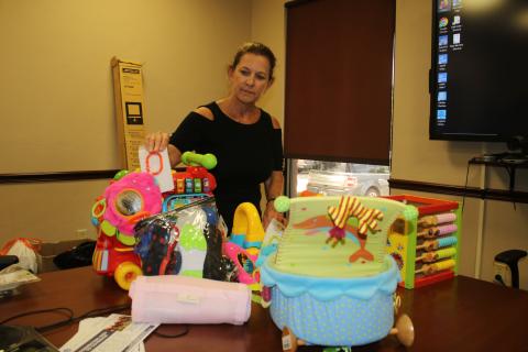 United Way of Suwannee Valley Executive Director Jennifer Anchors looks over some of the items that the organization will sell at its community yard sale Friday. (TONY BRITT/Lake City Reporter)