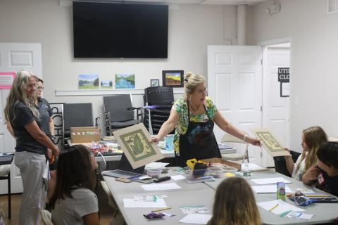 Laura Hunter-Null with the Gateway Art Gallery shows collages to students in an art literacy class Wednesday. The Gallery has partnered with Altrusa of Lake City on the program to teach literacy skills to children. (MORGAN MCMULLEN/Lake City Reporter)