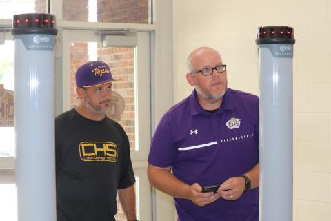 Columbia High Principal Trey Hosford (left) and Assistant Principal Doug Peeler test one of the portable metal detectors Monday at the CHS front entrance. (JAMIE WACHTER/Lake City Reporter)